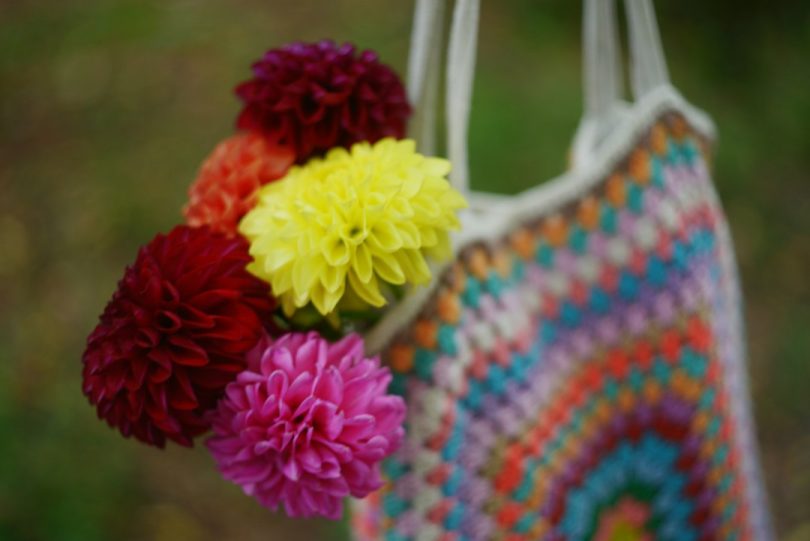 Colorful handmade crochet market bag holding a bouquet of flowers