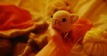 Crocheted cat head beside yarn balls; illustrative image for crochet cat projects