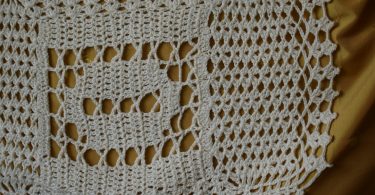 White crocheted lace motif illustrating filet crochet chartwork