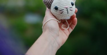 Small handmade crocheted cat head held in a hand; illustrative crochet image