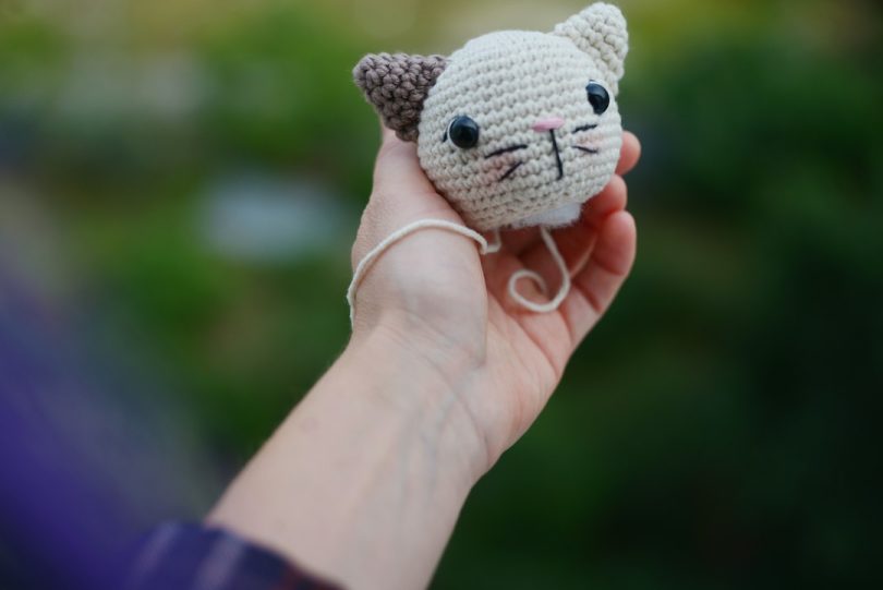 Small handmade crocheted cat head held in a hand; illustrative crochet image
