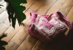 Pink and white handmade crochet tote bag on a wooden floor